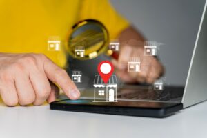 Person using a magnifying glass, a phone, and laptop looking for local businesses.